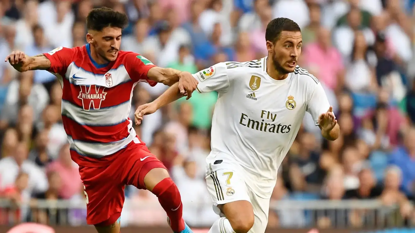 Real Madrid No.7 sprints past Granada defender during match — image for 1xBet Casino page